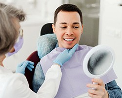 Man smiling at reflection in mirror with dentist