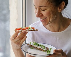 Woman smiling while eating snack next to window