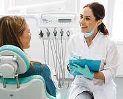 Smiling dentist taking notes while talking to patient